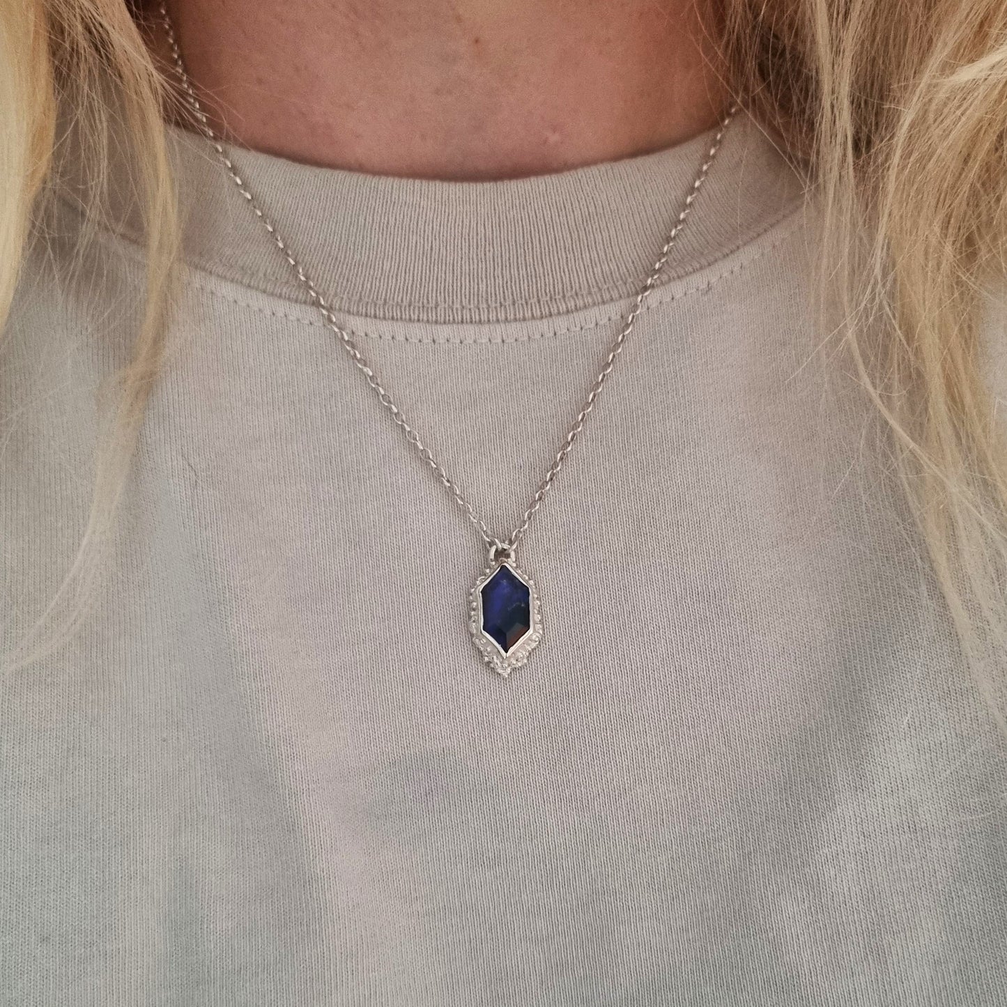 Necklace with a black opal pendant worn by a person against a neutral background