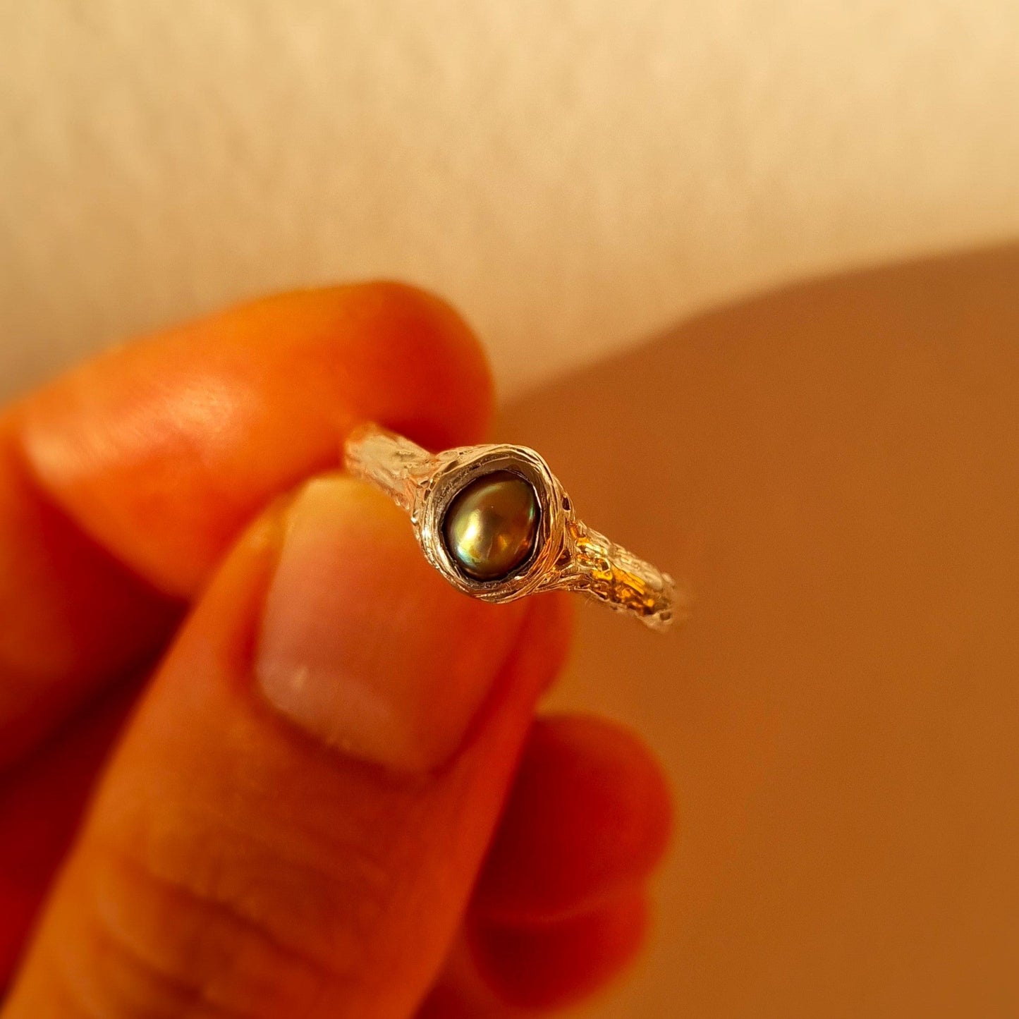 Organic Silver ring with paua pearl held between fingers. Elizabeth French Jewellery