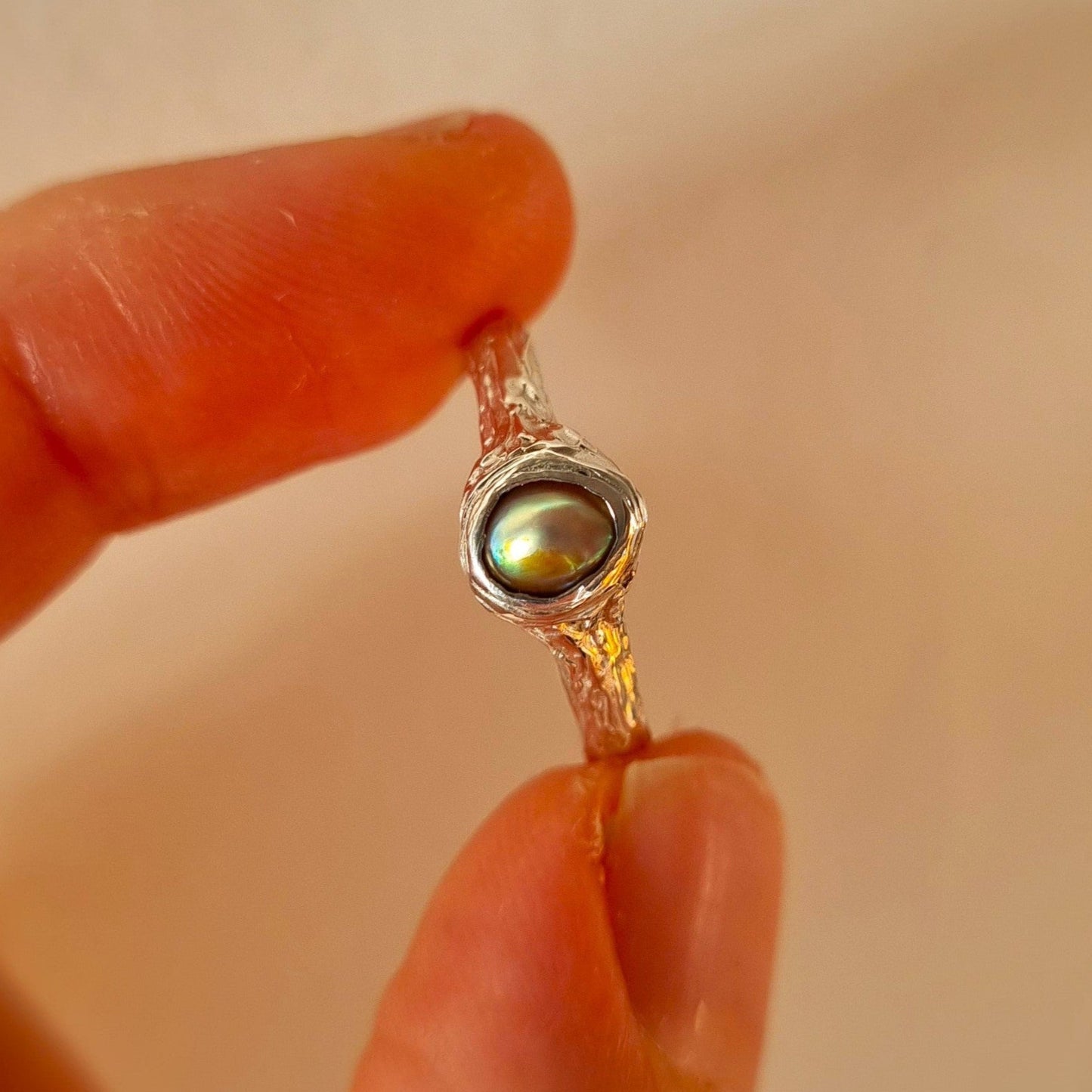 Sterling silver ring with paua pearl held between fingers. Elizabeth French Jewellery