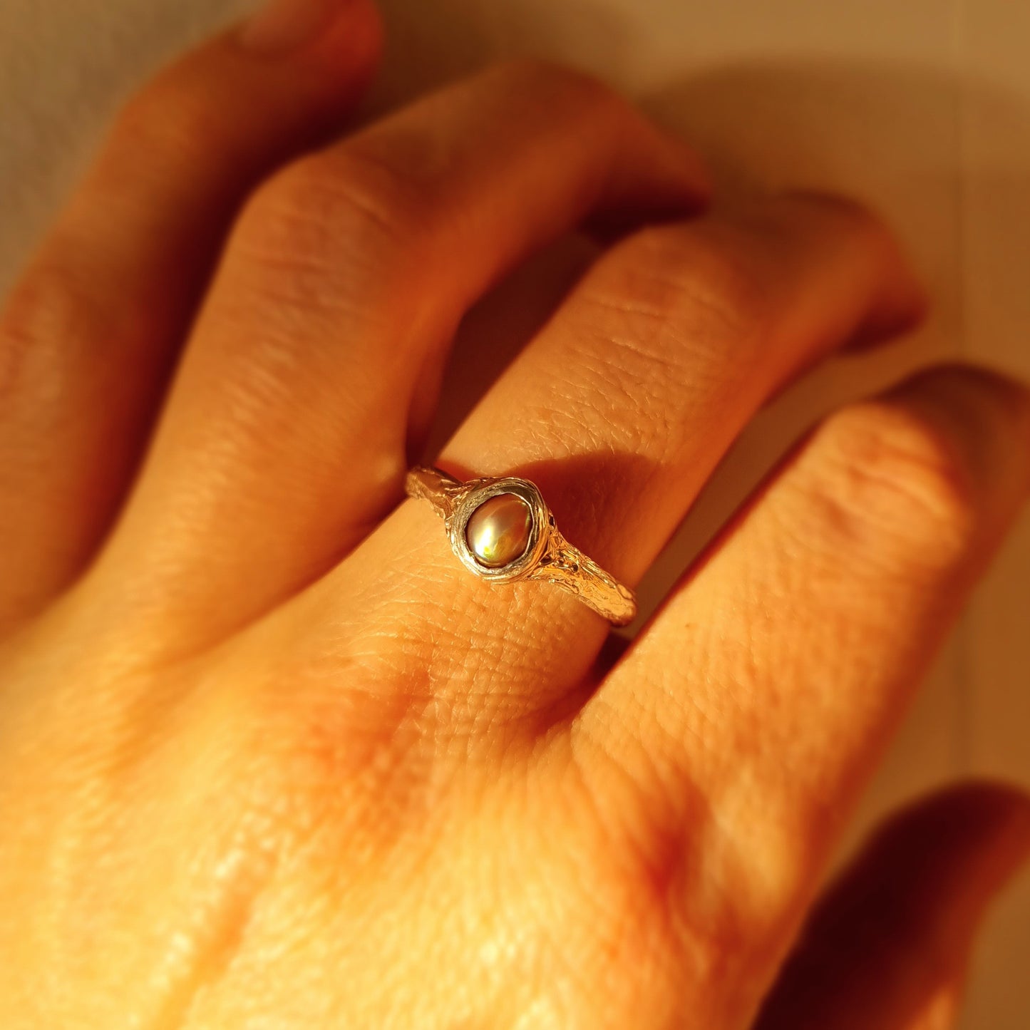 Close-up of a hand wearing a silver ring with a central paua pearl. Elizabeth French Jewellery