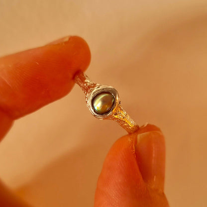 Silver ring with paua pearl held between fingers. Elizabeth French Jewellery