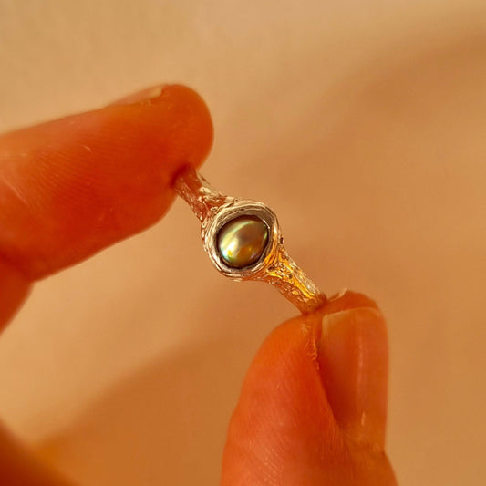 Silver ring with paua pearl held between fingers. Elizabeth French Jewellery