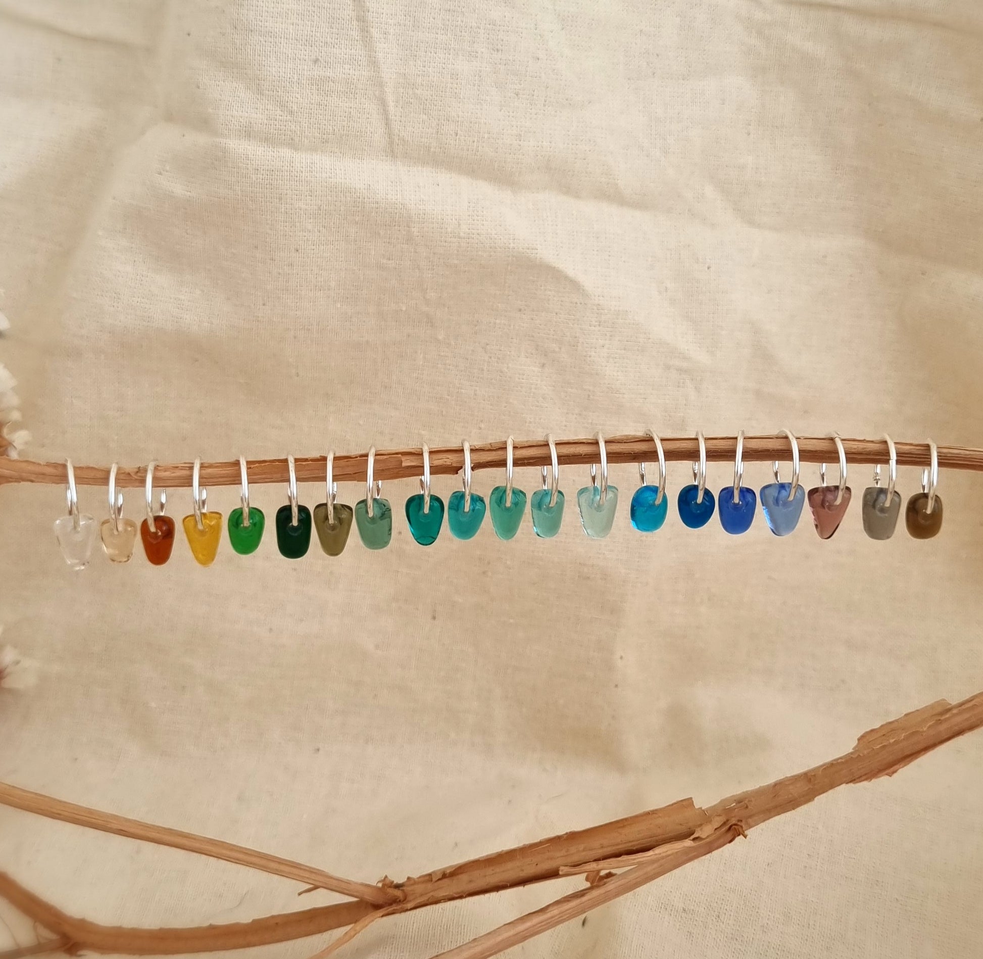 Colorful sea glass pieces on a stick against a beige background